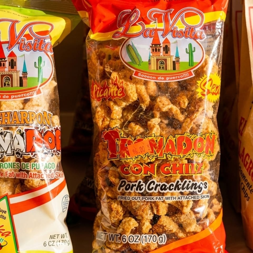 Bags of La Visita pork cracklings and El Milagro tortilla chips displayed in a store.